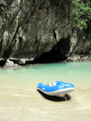 Refurbished dinghy with entrance to cave behind