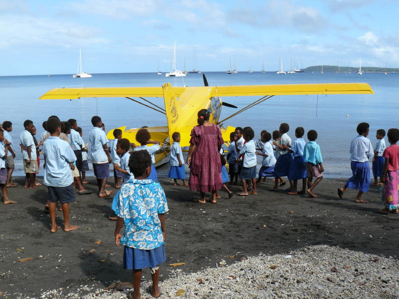 The yellow sea plane surrounded by children.