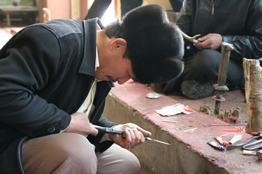 A Uighur man hunched over finishing off a hilt in the famous ‘knife town’ of Yengisar